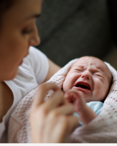 bebê chorando no colo da mãe com sono