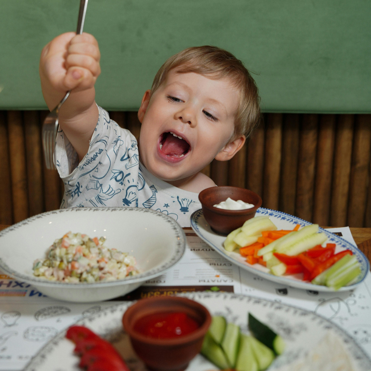 Criança comendo salada de legumes animadamente, ilustrando alimentação rica em fibras