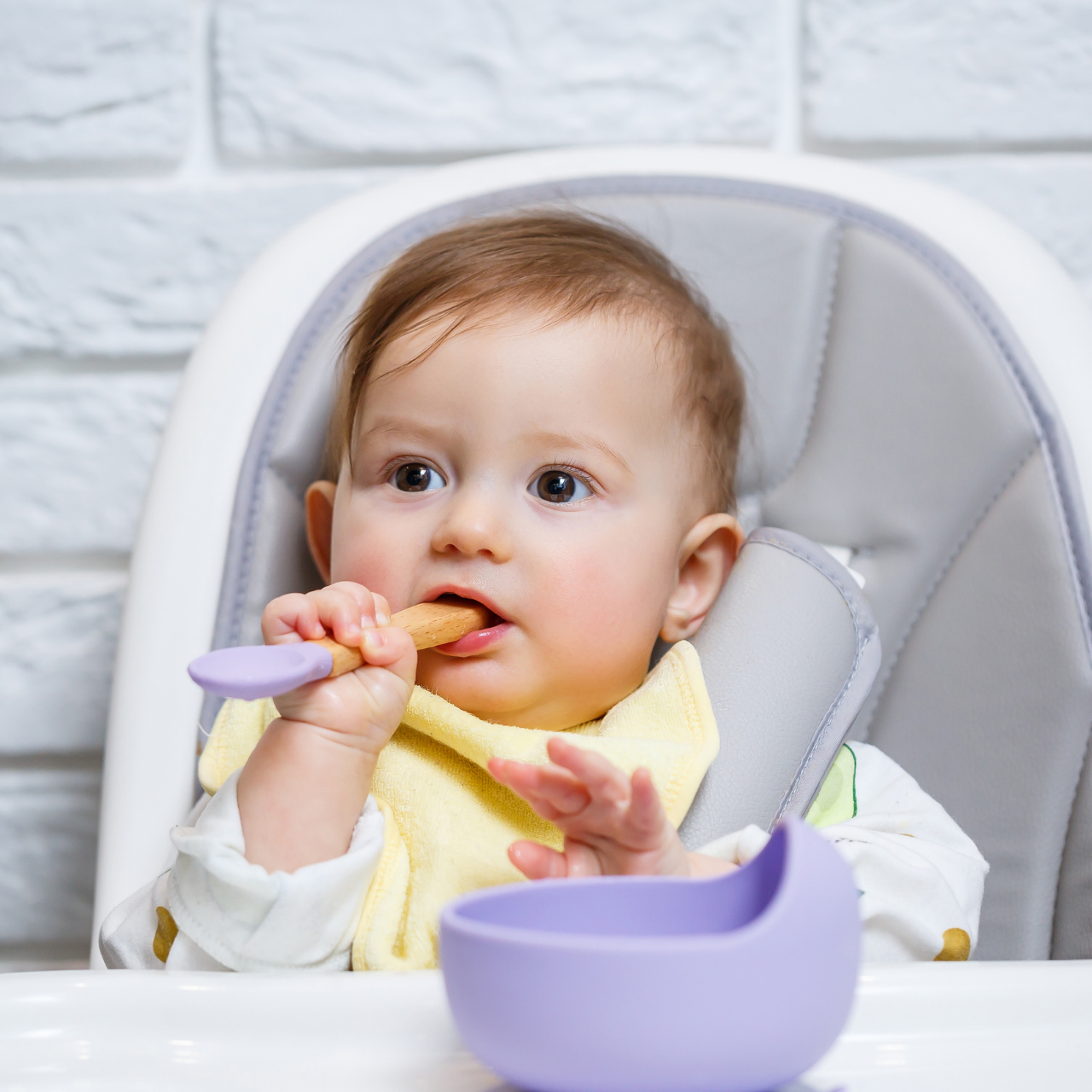 Bebê sentado na cadeirão comendo com colher, ilustrando alimentação rica em fibras