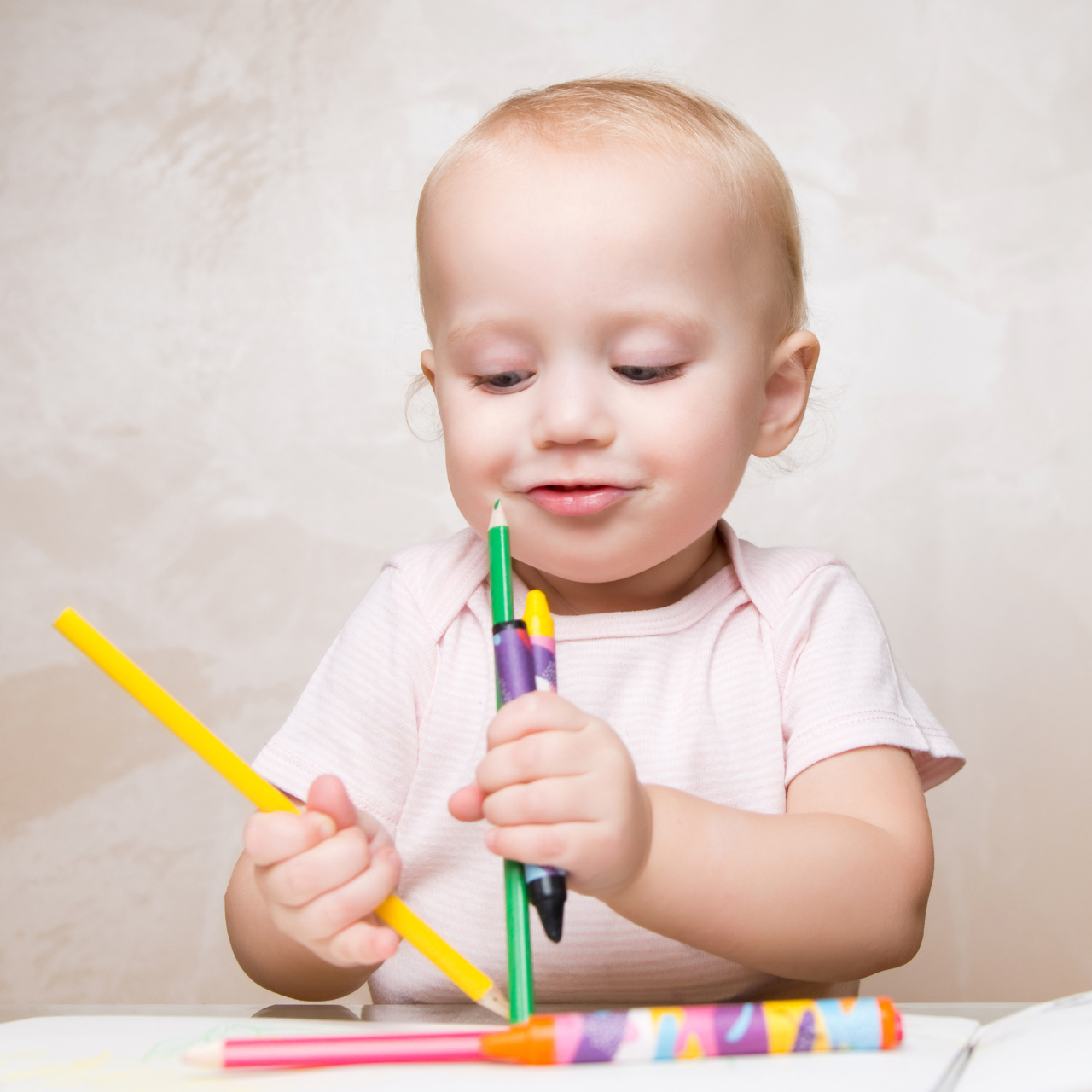Bebê explorando lápis de cor coloridos