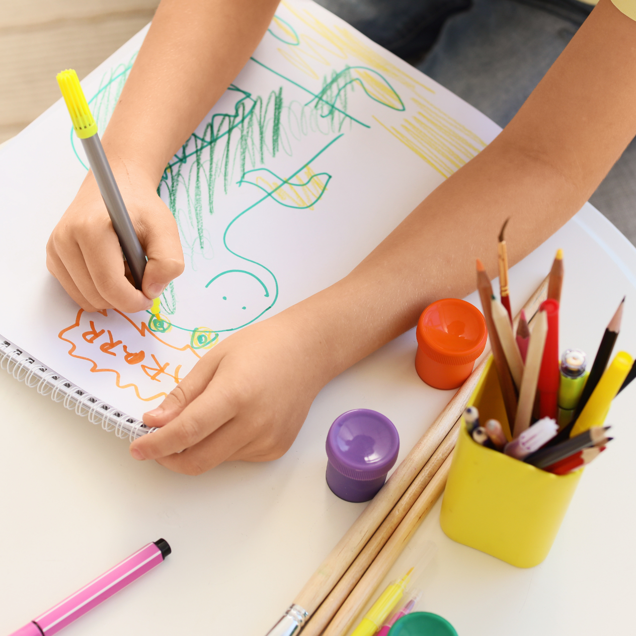 Criança pintando e desenhando com lápis de cor e giz de cera