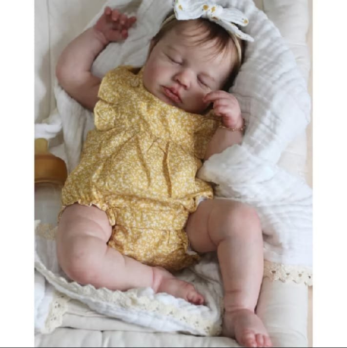Boneca bebê reborn dormindo com macacãozinho amarelo florido e laço na cabeça
