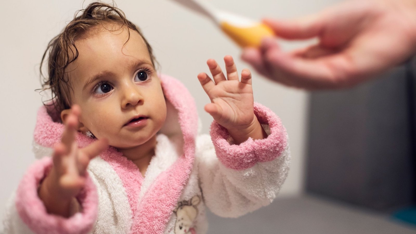 Bebê de roupão recebendo cuidados de higiene dos pais, parte da rotina antes de dormir