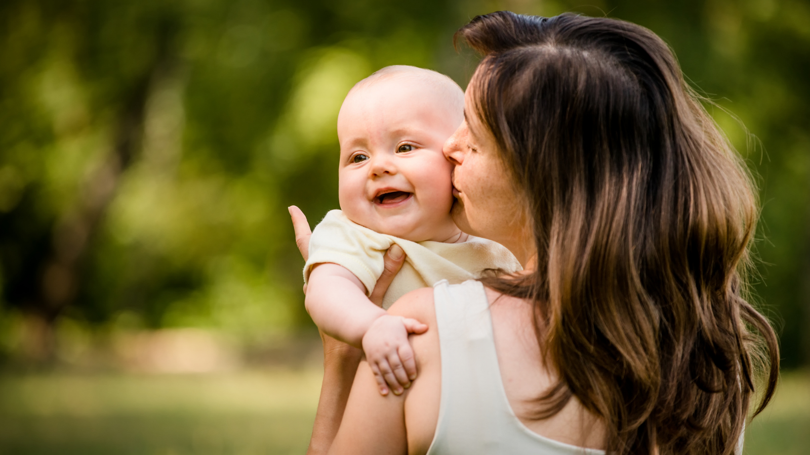 Mãe segurando bebê no colo com carinho, sorrindo