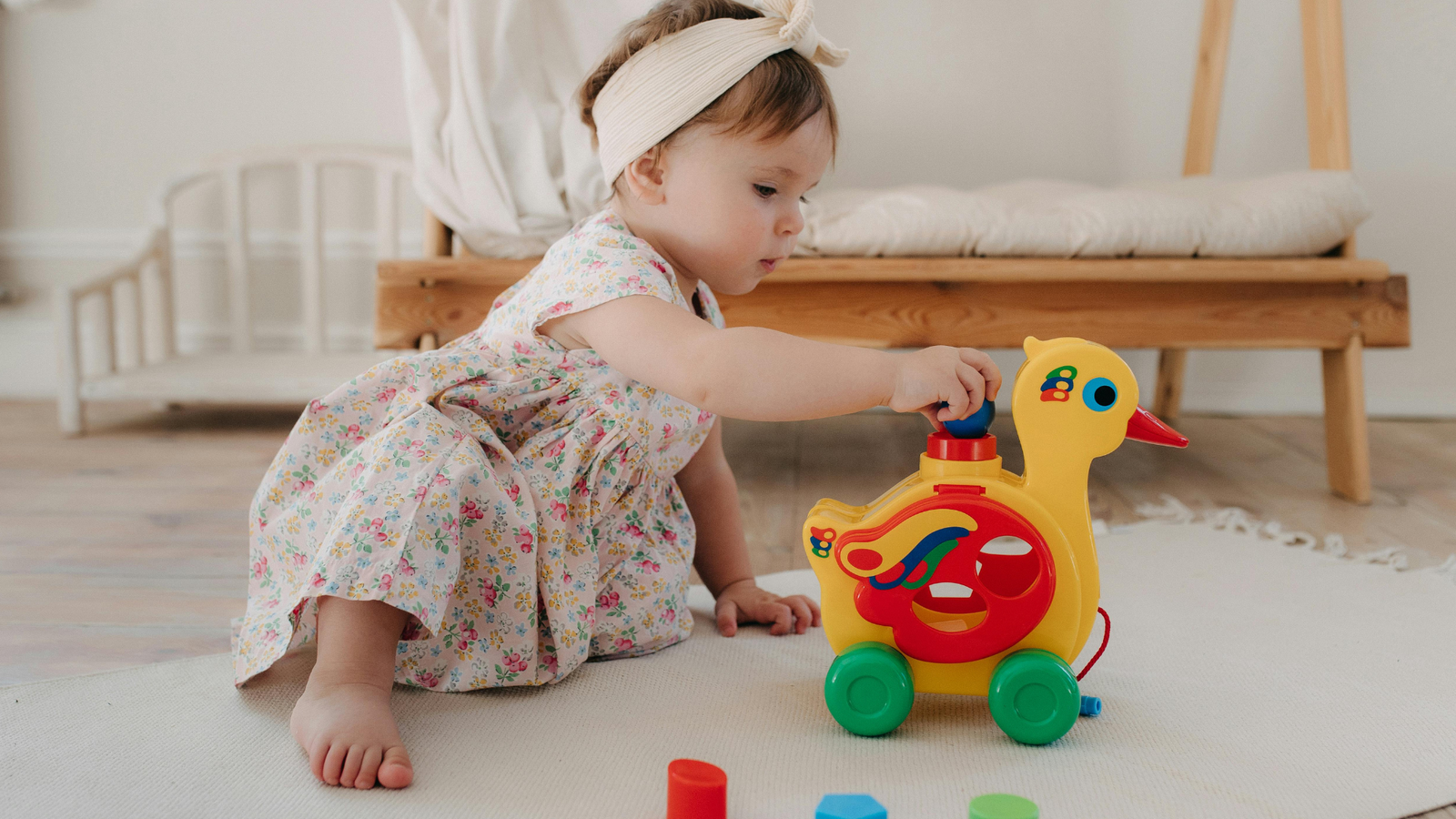 Bebê concentrado brincando com brinquedo de pato colorido em tapete