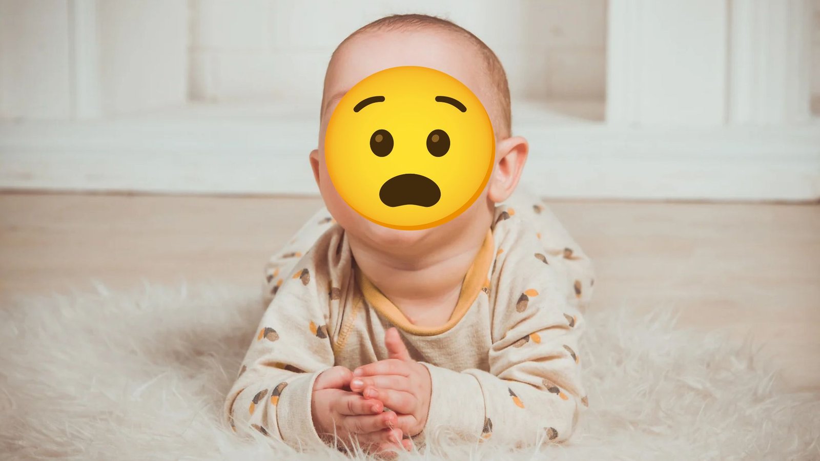 Bebê de bruços no tapete com expressão de susto