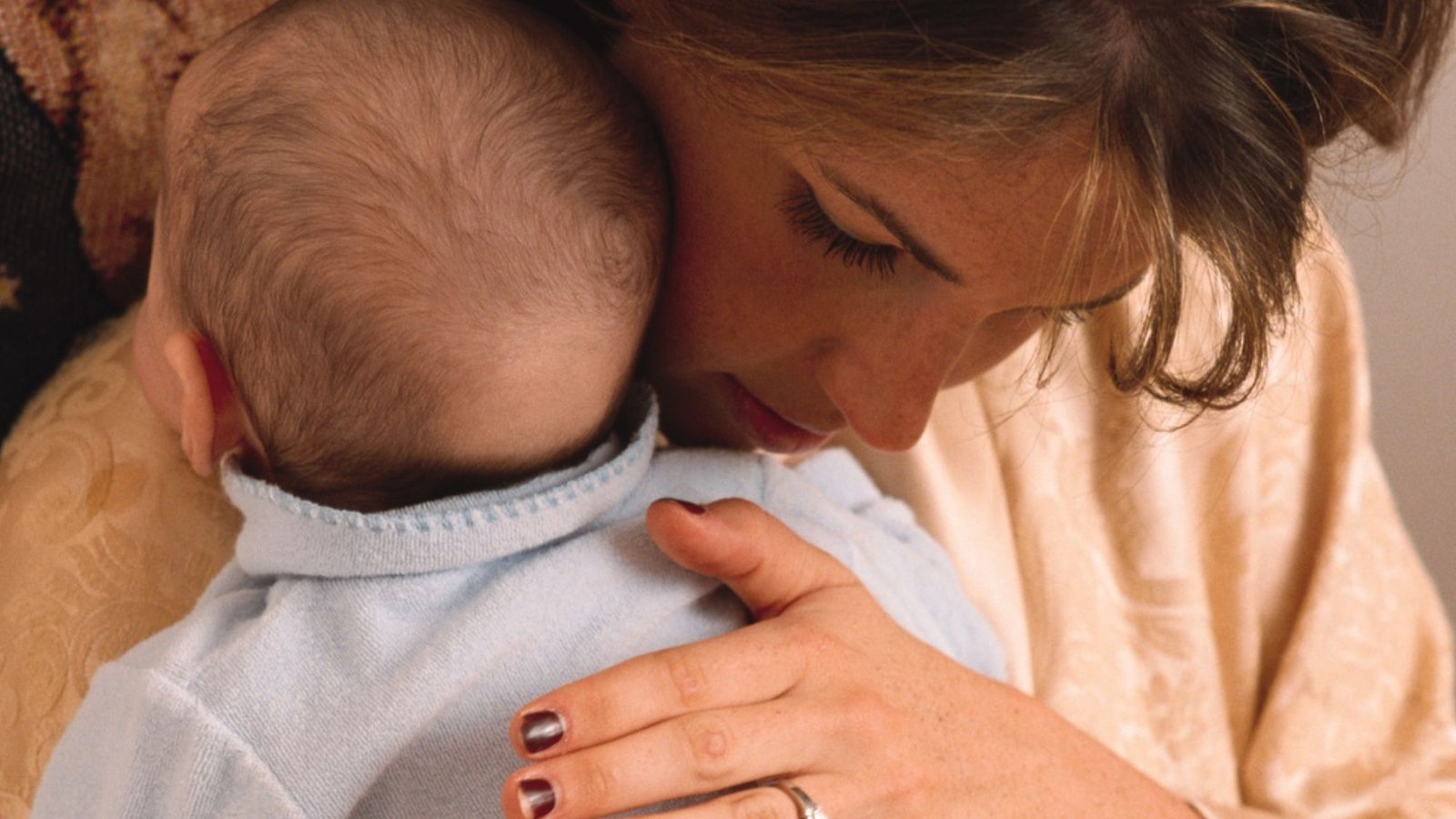 Bebê recém-nascido aconchegado no colo da mãe, tranquilo, depois da mamada