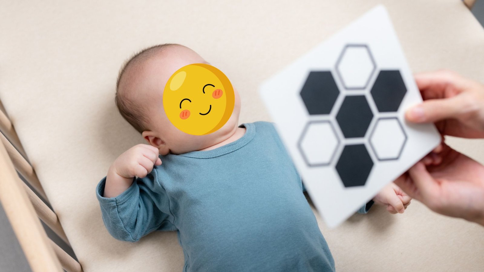 Bebê deitado no berço olhando um cartão de alto contraste com hexágonos pretos e brancos segurado por um adulto